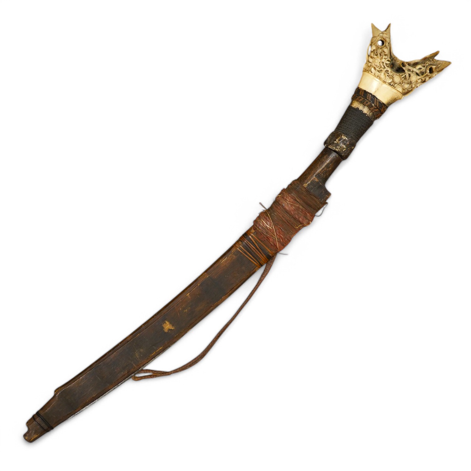 An elaborate Dayak headhunter’s sword Mandau, curved blade with chiselled and engraved back edge, large bone grip carved with protruding teeth, etc. in its wooden scabbard. Condition - good, some age wear.
